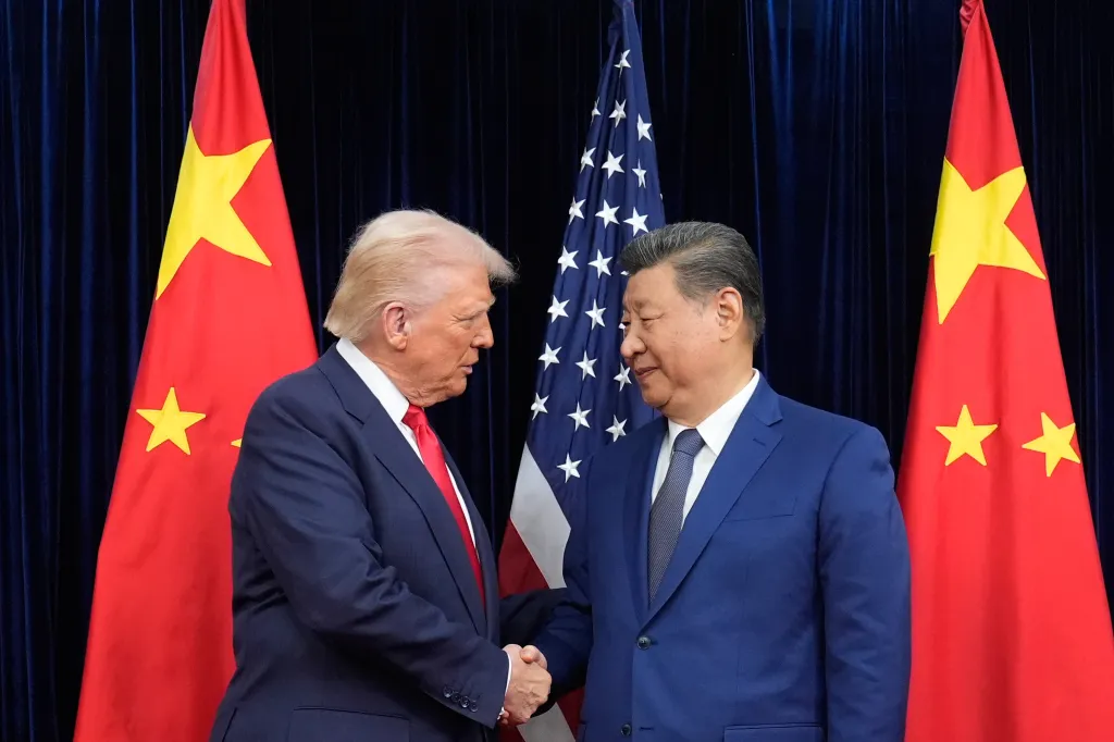Donald Trump and Xi Jinping shaking hands, with the US and Chinese flags behind them.