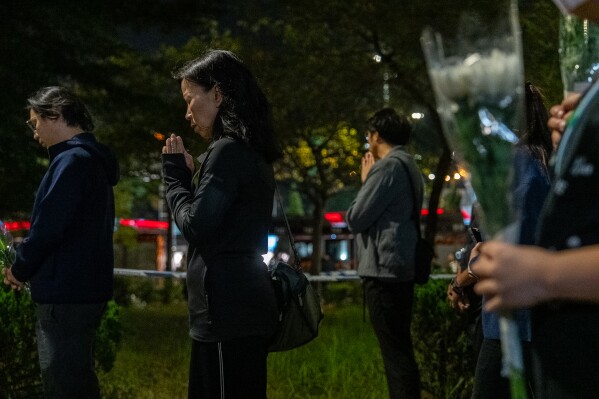 People offer flowers and pray for the victims near the site of Wednesday's fire at Wang Fuk Court, a residential estate in the Tai Po district of Hong Kong's New Territories, Sunday, Nov. 30, 2025. (AP Photo/Chan Long Hei, File)