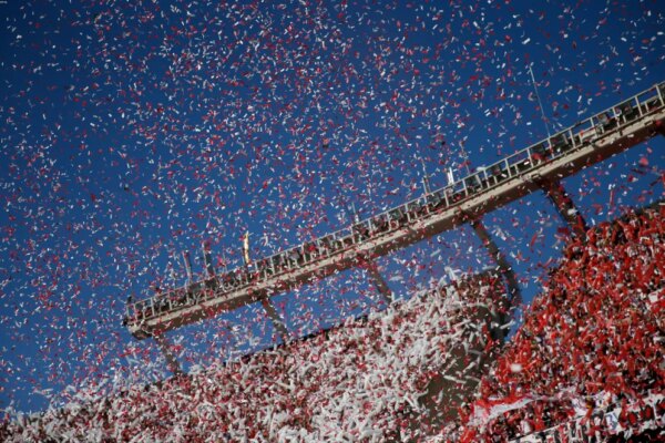 fans in a soccer stadium throwing white and red confetti
