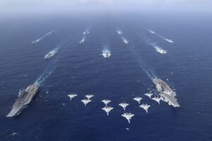 Image showing aircraft flying overhead two aircraft carriers and their escorts.