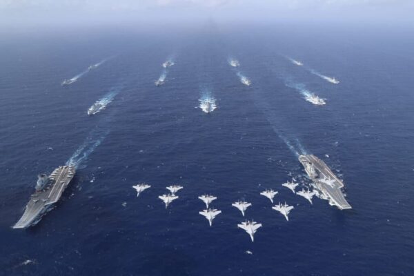 Image showing aircraft flying overhead two aircraft carriers and their escorts.