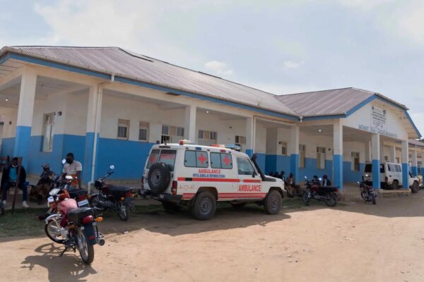 People wait near an ambulance at a hospital.