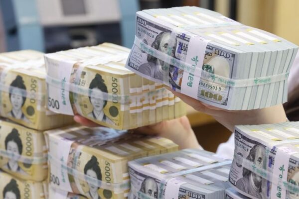 An employee arranges U.S. dollar bills and 50,000 won notes at a branch of Hana Bank in central Seoul, April 3. Yonhap