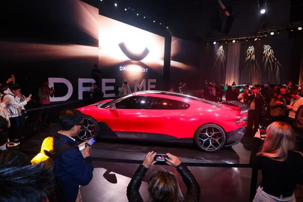electric sports car showcased at an event with an audience