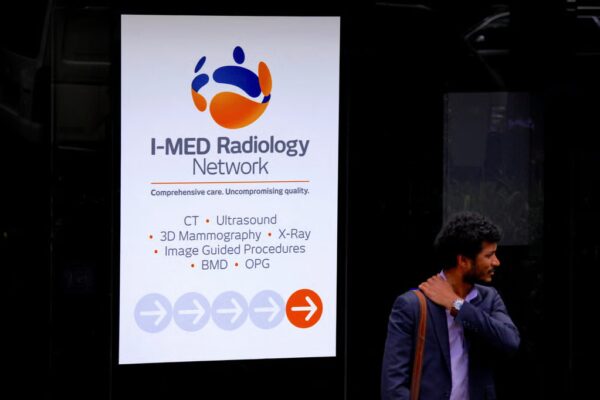 A pedestrian stands next to a banner for Australia’s I-MED Radiology Network in Sydney. Photo: Reuters
