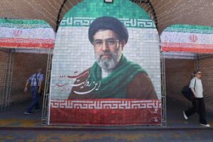 Iranian commuters walks past a large tiled image of Iran's current leader Ayatollah Mojtaba Khamenei, at the entrance to the metro in Tehran. (AFP)