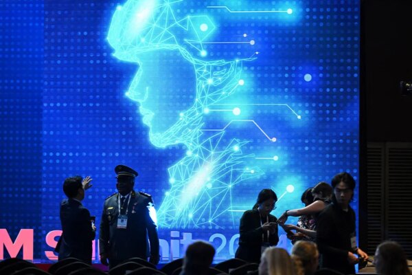 Participants chat in front of an electronic image of a soldier at the Responsible AI in the Military Domain summit in Seoul