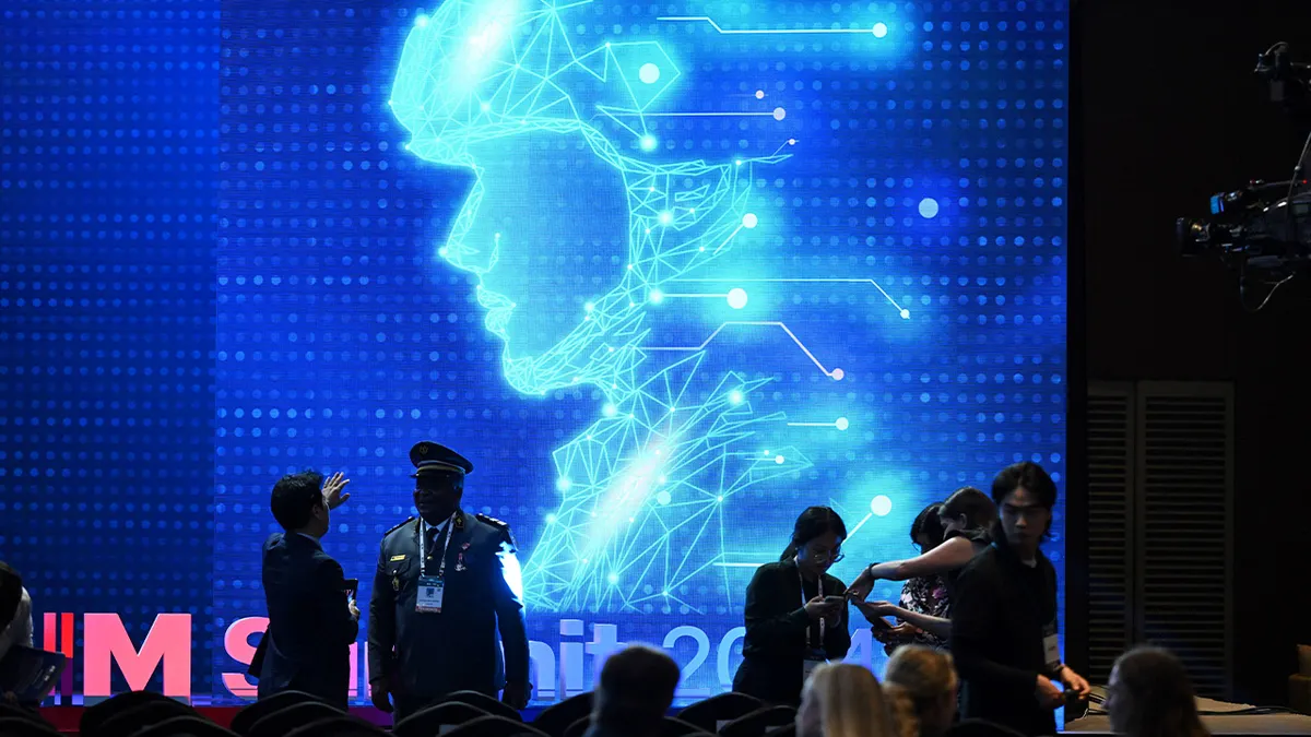Participants chat in front of an electronic image of a soldier at the Responsible AI in the Military Domain summit in Seoul