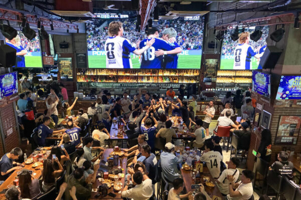 Chinese fans in blue Japan jerseys at a Shanghai cheer after a goal in the 4-0 win over Tunisia