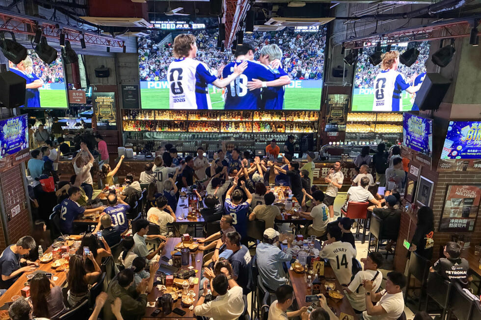 Chinese fans in blue Japan jerseys at a Shanghai cheer after a goal in the 4-0 win over Tunisia