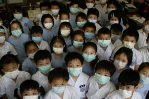 S.K.H. St. Peter’s Primary School students in Shek Tong Tsui prepare to take off their face masks after the World Health Organization announced the removal of Hong Kong from a list of Sars-affected areas. June 23, 2003. Photo: Oliver Tsang