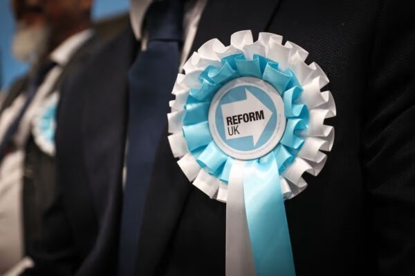 A person wearing a Reform UK rosette