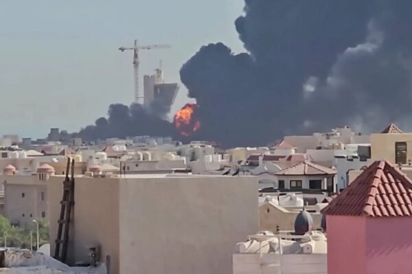 Thick black smoke and orange flames rise into the sky over buildings in Kuwait.
