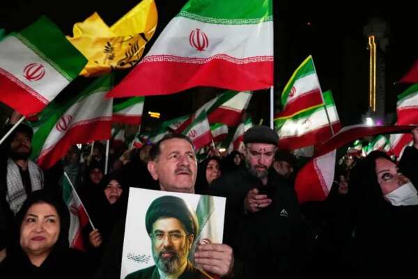 Government supporters walk past a billboard depicting Iran's Supreme Leader Mojtaba Khamenei. (AP Photo)