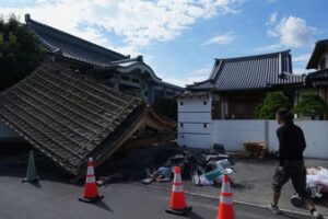 A man helps clean the damaged gate of Jofukuji Buddhist temple in Kumamoto, southwestern Japan, Wednesday, July 29, 2026, the day after an earthquake hit the area. (AP Photo/Hiro Komae) (AP Photo/Hiro Komae)