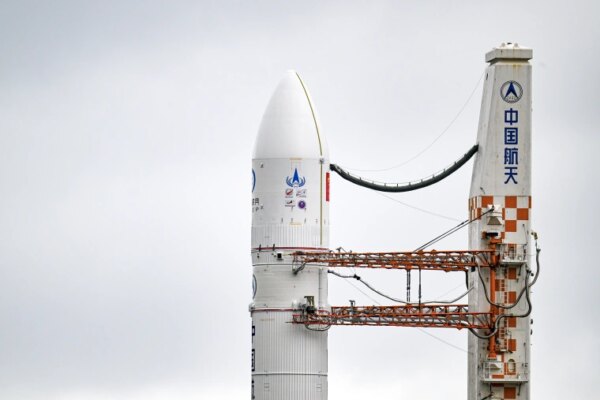 A rocket and booster rise against a gray sky.