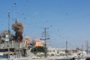 People run for cover, as debris flies through the air, during an Israeli strike, carried out after the Israeli military warned residents to evacuate the area, Al-Zawayda, in the central Gaza Strip, (Reuters)