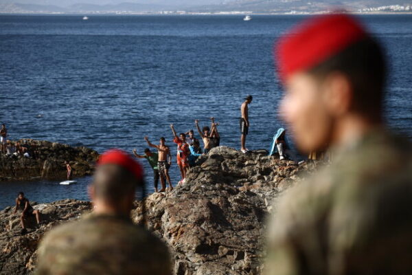 TOPSHOT - Members of the Spanish Army's 'Regulares' infantry forces watch a group of migrants near the border post of the Spanish enclave of Ceuta on August 2, 2026. At least 72 people died during last week's mass influx of migrants into Spain's Ceuta enclave, when tens of thousands of people mostly swam around the border post from Morocco, local officials said today. Most of the estimated 60,000 people who rushed into Spain's north African territory have returned to Morocco since the territory's largest mass migrant crossing. (Photo by Henry NICHOLLS / AFP via Getty Images)