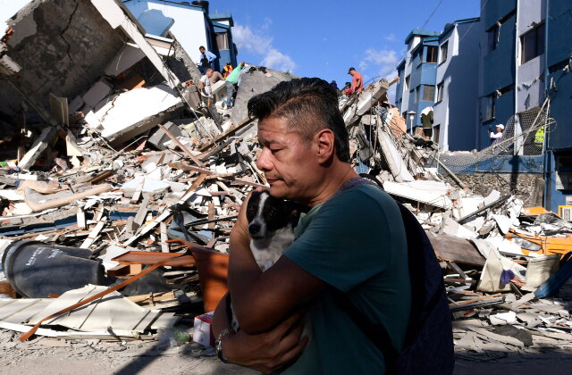 TOPSHOT - A man carries a dog as he walks past the rubble of a collapsed building after an earthquake in Pereira, Colombia on August 10, 2026. A powerful earthquake rocked Colombia and neighboring Latin American countries on August 10, 2026, with medical teams rushing to help victims after buildings were damaged or collapsed in several cities. The Colombian geological service and its American counterpart USGS put the magnitude at 7.4, with an epicenter 100 km (60 miles) underground in the west of the country. Colombia had initially put it at 6.6. (Photo by Jaime SALDARRIAGA / AFP via Getty Images)