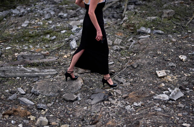 A woman walks across the debris in the aftermath of an overnight Russian missile and drone attack on Kyiv, Ukraine, Thursday, Aug. 20, 2026 (AP Photo/Francisco Seco)