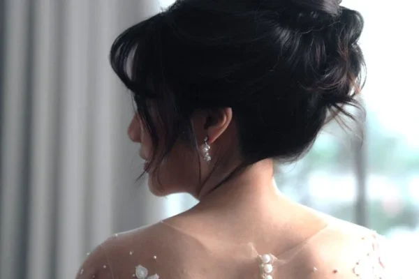A bride with her in an updo looks over her shoulder.