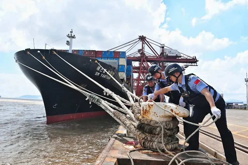 In this photo released by Xinhua News Agency, police officers check the mooring lines of a vessel ahead of Typhoon Dolphin in Beilun District of Ningbo City, east China's Zhejiang Province, on Aug. 7, 2026.(Hu Jiajie/Xinhua via AP) - The Associated Press