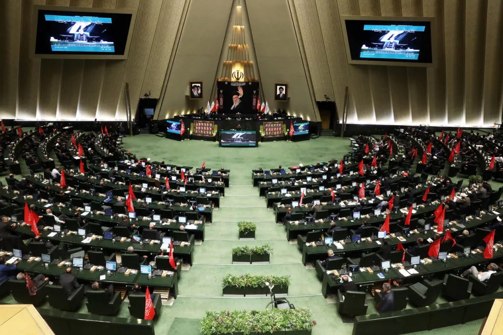 Iranian Parliament session with lawmakers holding red religious flags.