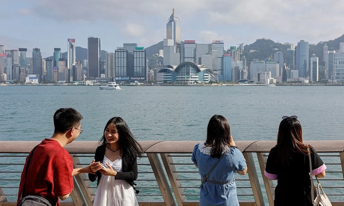 Tourists take photo of the skyline of buildings at Tsim Sha Tsui, in Hong Kong, China, May 2, 2023. Photo by Reuters