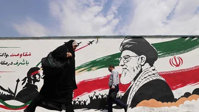 Pedestrians walk past a wall mural of Iran's slain supreme leader Ayatollah Ali Khamenei, along a street in downtown of Tehran on August 31. (AFP)
