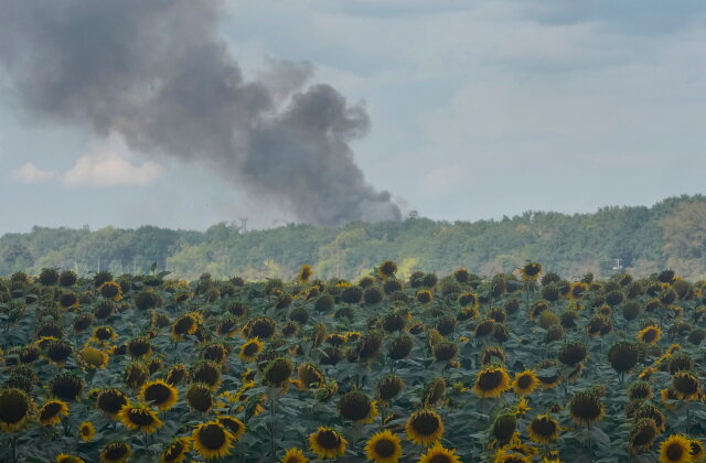 Smoke rises above warehouse stores behind a sunflower field following a Russian air attack in Kyiv, Ukraine, Thursday, Aug. 27, 2026. (AP Photo/Efrem Lukatsky)